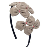 A beige and black grosgrain headband adorned with multiple bows with pink stitching on a white background.